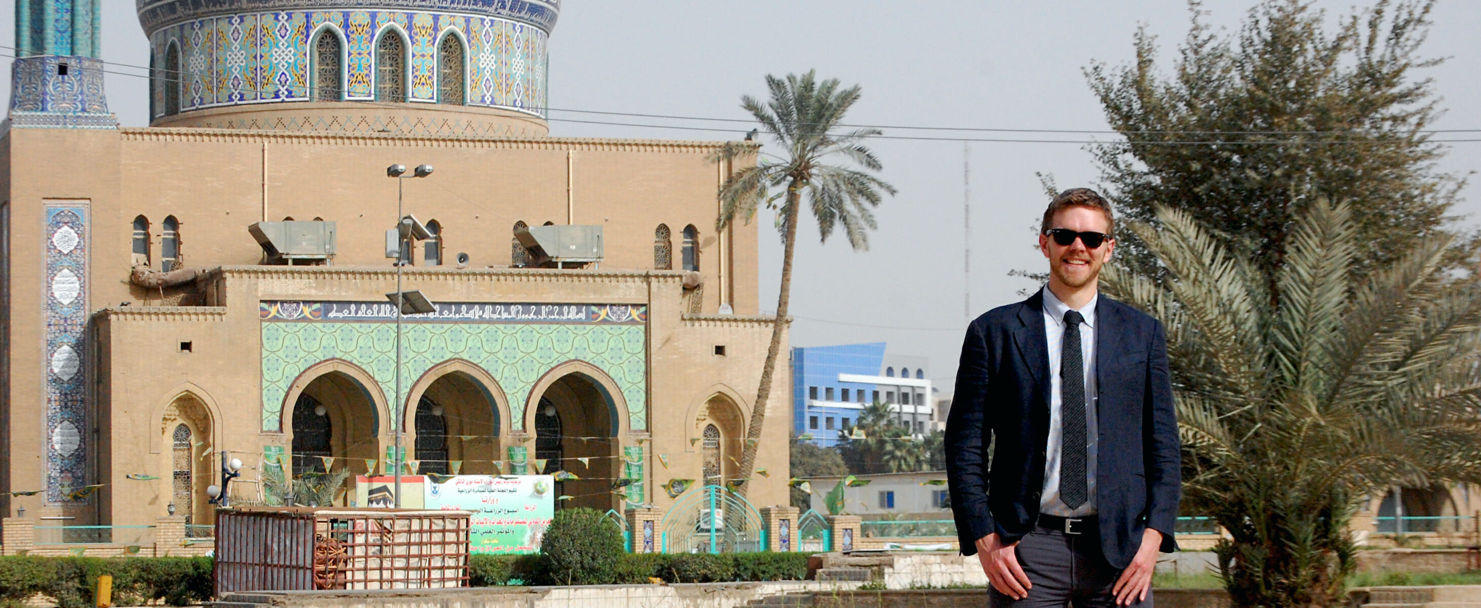 Ben Van Heuvelen in Baghdad, standing next to a mosque.