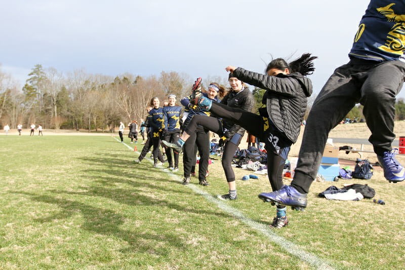 Michigan's sideline does a kick-cheer at Queen City Tune Up 2019.