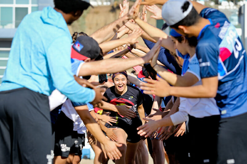 A youth player runs through a tunnel of Live Ultimate ambassadors at the Beach of Dreams event. Photo: Kristina Geddert -- UltiPhotos.com