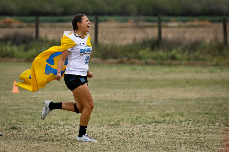 UCLA's Olivia Sandom rushes the field in celebration with a school flag at Stanford Invite 2020. Photo: Kristina Geddert -- UltiPhotos.com