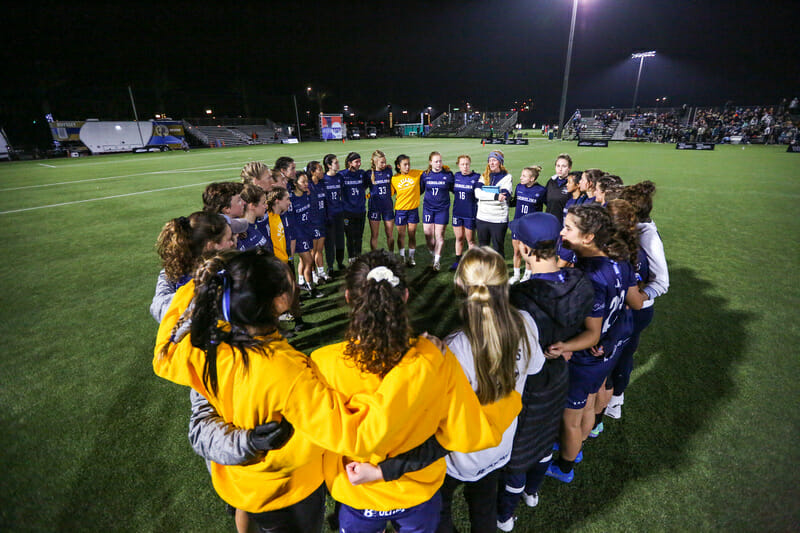 North Carolina Pleiades huddles with coach Jessi Jones at the 2021 D-I College Championships in Norco, CA.