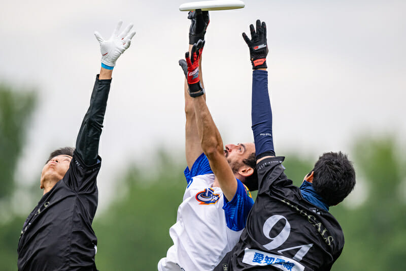 Baja Ultimate makes a catch over two Rascals players at WUCC 2022. Photo: Sam Hotaling -- UltiPhotos.com